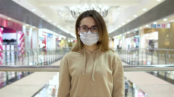 Una joven con máscara médica en el centro comercial. La mujer enmascarada se protege de la epidemia del virus chino. La cámara se acerca a una mujer 2019-nKoV — Foto de Stock