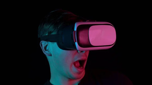 Fiatal férfi a Vr szemüveges közelből. Egy ember, aki belemerül a virtuális valóságba, mozdulatokat tesz a kezével. Kék és piros fény esik egy ember a fekete háttér. — Stock Fotó