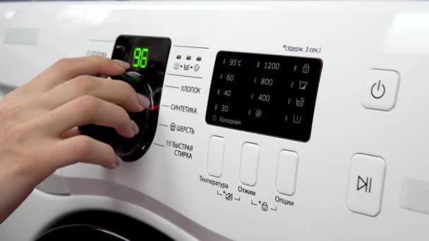 A young woman turns on a washing machine. A woman turns the lever choosing the mode on the washing machine and turns it on. Hand close-up. — Stock Video