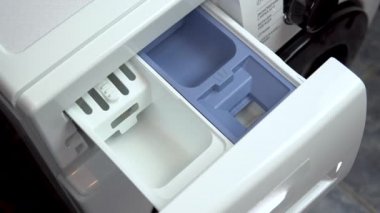 Çamaşır makinesindeki tozu doldurur.