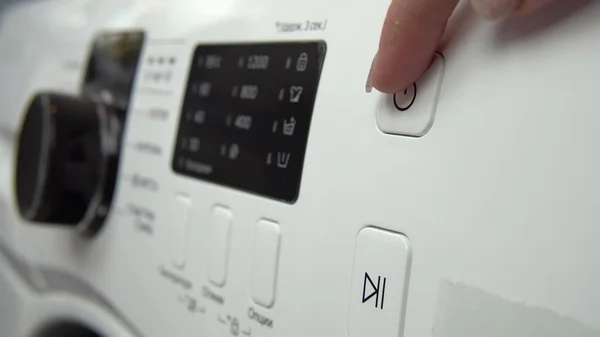 A young woman turns on a washing machine. Hand close-up. — Stock Photo, Image