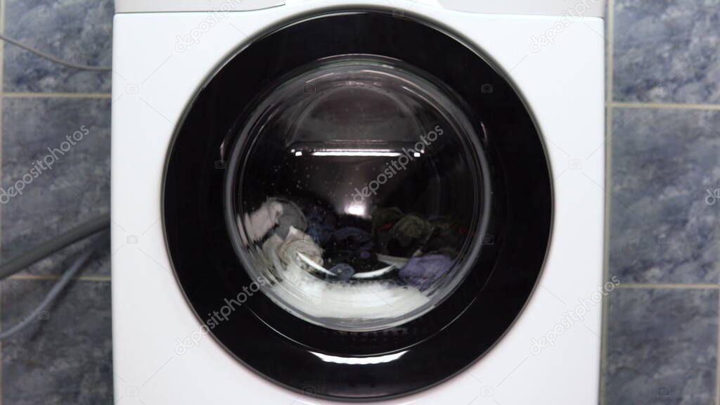 The washing machine is working. A washing machine spins a drum filled with clothes.