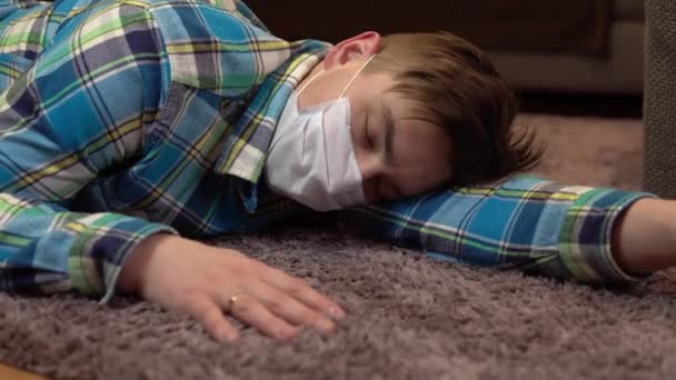 床の上に若い男が横たわっている。医療マスクの男が意識不明の床の上に横たわっている. — ストック動画
