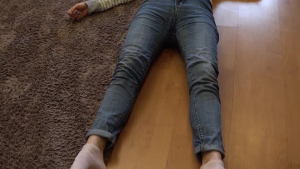 Μια νεαρή γυναίκα κείτεται νεκρή στο πάτωμα. Μια γυναίκα με ιατρική μάσκα βρίσκεται στο πάτωμα της αναισθησίας. Άποψη από ψηλά. — Αρχείο Βίντεο