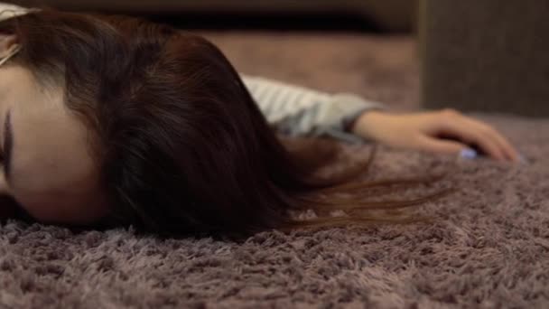 한 젊은 여자가 죽은 채 바닥에 누워 있습니다. 의료용 마스크를 쓴 한 여자가 의식을 잃은 채로 바닥에 누워 있다. — 비디오