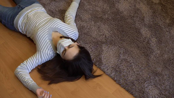 Μια νεαρή γυναίκα κείτεται νεκρή στο πάτωμα. Μια γυναίκα με ιατρική μάσκα βρίσκεται στο πάτωμα της αναισθησίας. Άποψη από ψηλά. — Φωτογραφία Αρχείου