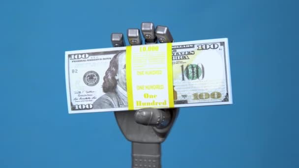 Una mano mecánica sostiene un paquete de dólares. Una mano cyborg gris sostiene el dinero sobre un fondo azul . — Vídeos de Stock