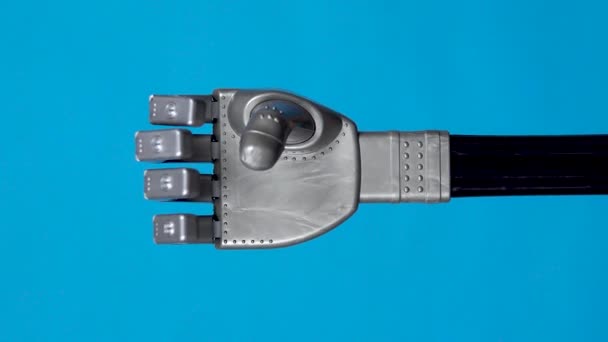 Ein mechanischer Arm beugt die Finger vor. Der graue Cyborg-Arm erwachte zum Leben und begann sich auf blauem Hintergrund zu bewegen. Vertikales Video — Stockvideo