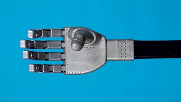 Ein mechanischer Arm beugt die Finger vor. Der graue Cyborg-Arm erwachte zum Leben und begann sich auf blauem Hintergrund zu bewegen. Vertikales Video — Stockvideo