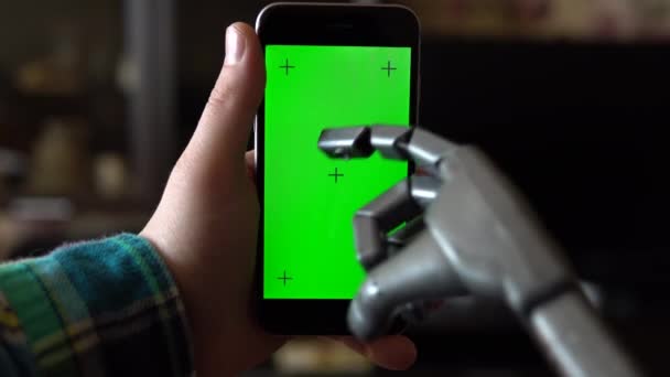 Cyborg benutzt das Telefon. Eine graue mechanische Hand drückt auf ein Smartphone mit grünem Bildschirm. Chroma-Schlüssel. — Stockvideo