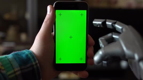 Cyborg gebruikt de telefoon. Grijze mechanische handveeg omhoog op smartphone met groen scherm. Chromatoetsen. — Stockvideo