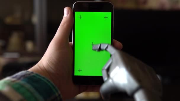 Киборг пользуется телефоном. Серая механическая рука печатает на смартфоне с зеленым экраном. Ключ хрома . — стоковое видео