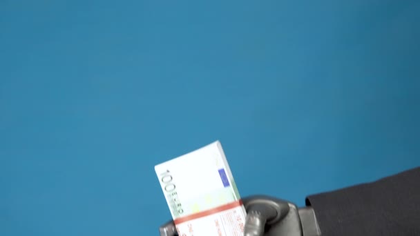 Cyborg businessman in a suit holds out a wad of euros to a woman. Businesswoman takes money from a gray mechanical hand. Hands closeup on a blue background. — Stock Video