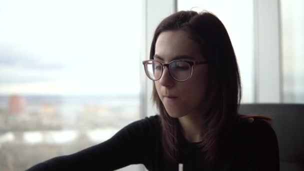 Kızarmış patates yiyen genç bir kadın. Bir kız panoramik pencerenin yanındaki kafede oturur ve fast food yer.. — Stok video