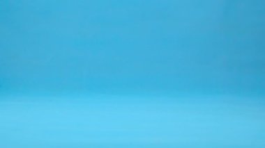 Gözleri olan limon yavaşça yuvarlanır. Mavi arka planda ekmekleri olan limon. Yavaş çekim.