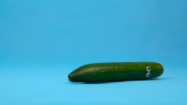 Cucumber with eyes falls slowly. Cucumber fell on a blue background. Slow motion. — Stock Video