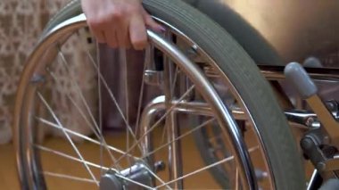 Tekerlekli sandalyedeki genç kadın. Kız odada tekerlekli sandalyeyle dolaşıyor. Yakın plan el..