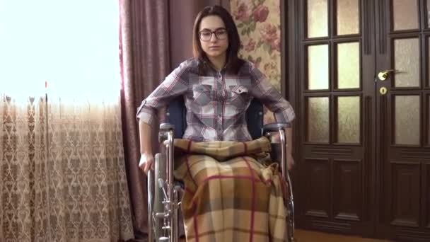Молодая женщина в инвалидном кресле. Девушка переезжает в инвалидной коляске по дому. Девушка приближается к камере . — стоковое видео