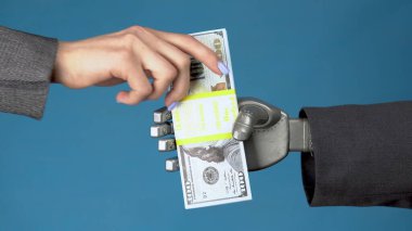 Takım elbiseli bir Cyborg işadamı bir kadına bir tomar para veriyor. İş kadını gri mekanik elden para alıyor. Eller mavi arka planda. 4k