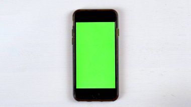 Masanın üzerinde yeşil ekranlı bir telefon var. Gadget Ekranında Krom Anahtar.