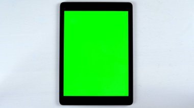 Masanın üzerinde yeşil ekranlı bir tablet var. Gadget Ekranında Krom Anahtar.