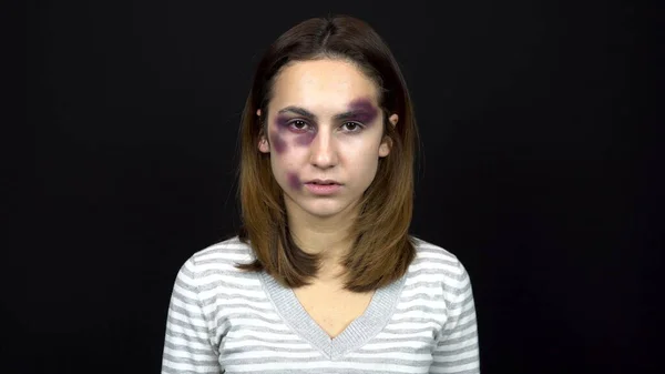 Young woman with bruises on her face. Quarrel in a young family. Domestic violence. On a black background. — Stock Photo, Image