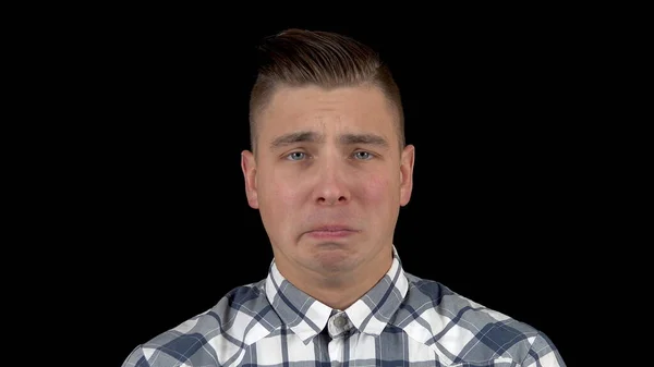 O jovem está a chorar. Homem emocional chorando em um fundo preto closeup — Fotografia de Stock
