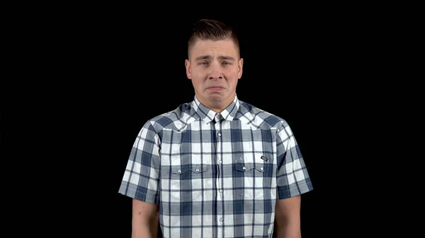 Un joven muestra una emoción de tristeza. Hombre triste en una camisa sobre un fondo negro — Foto de Stock