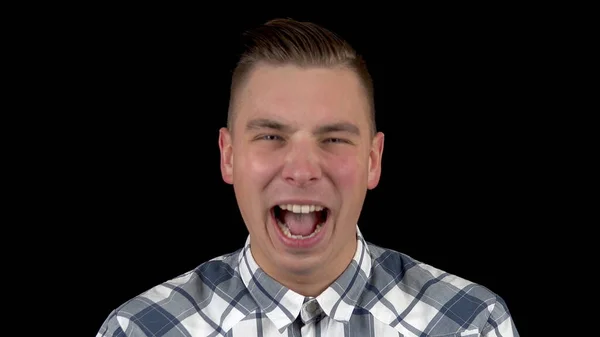 De jongeman toont de emotie van het lachen. Een man lacht in een shirt op een zwarte achtergrond close-up — Stockfoto