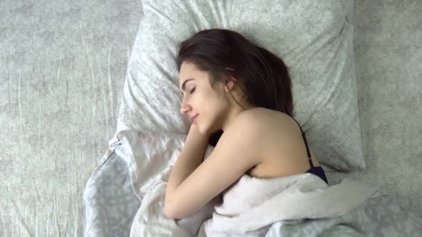 Una giovane donna dorme sotto le coperte. Una ragazza giace a letto nella sua stanza. Vista dall'alto. — Video Stock