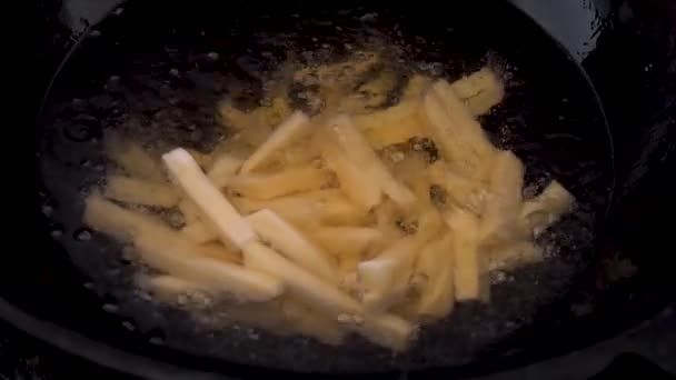 Kızgın yağlı tavada patates kızartması. Yakından bakınca dilimlenmiş patatesler kaynıyor. Yavaşça. — Stok video