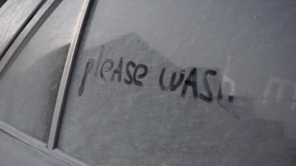 На грязной машине написано: "Пожалуйста, вымой меня". Шутка над владельцем черной машины. — стоковое видео