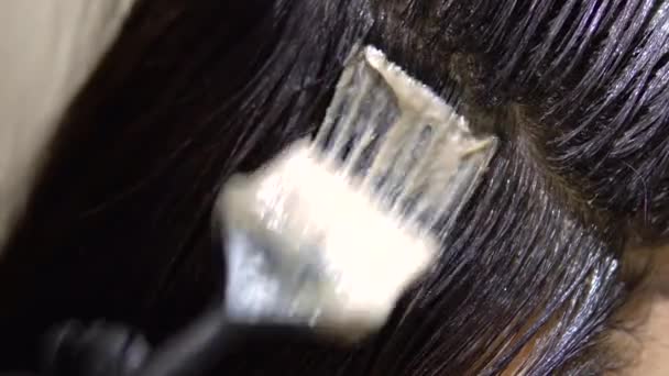 Femme teindre ses cheveux avec un pinceau gros plan. La brune est peinte dans le salon par un professionnel.