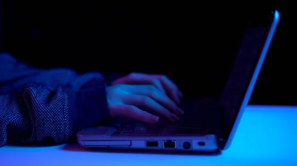 Una giovane donna sta digitando su una tastiera di un computer portatile. Chiudete le mani. L'hacker ha hackerato un portatile. Luce blu e rossa cade sulle mani . — Foto Stock