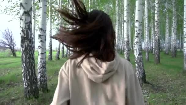 Молода жінка проходить через березовий ліс у повільному русі. Дівчина біжить між деревами. Вид ззаду . — стокове відео