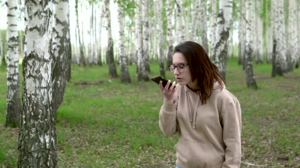 Uma jovem procura uma rede celular numa floresta de bétulas. Uma rapariga está a falar ao telefone, mas a ligação é interrompida. A mulher está nervosa. . — Vídeo de Stock