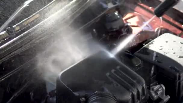 Spoelt vuil van een automotor weg met een hogedrukwaterstraalclose-up. Speciaal wasmiddel voor carwash. Wast een auto voor het huis. — Stockvideo