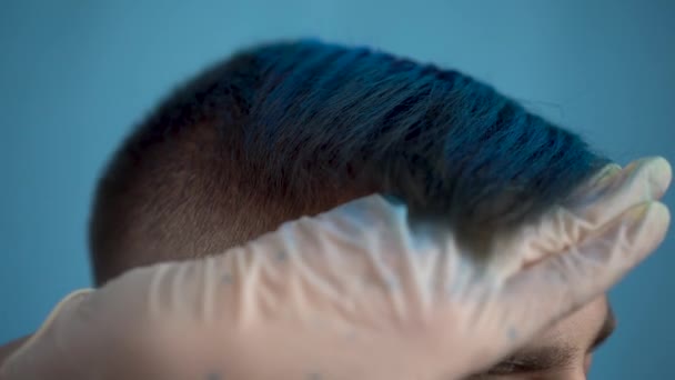 Un jeune homme est teint ses cheveux en gros plan bleu. Une personne alternative est peinte avec de la teinture capillaire temporaire d'une boîte de pulvérisation. — Video