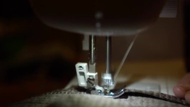 Dikiş makinesinde giysileri yakın plan dikerim. Terzi kumaş dikiyor..