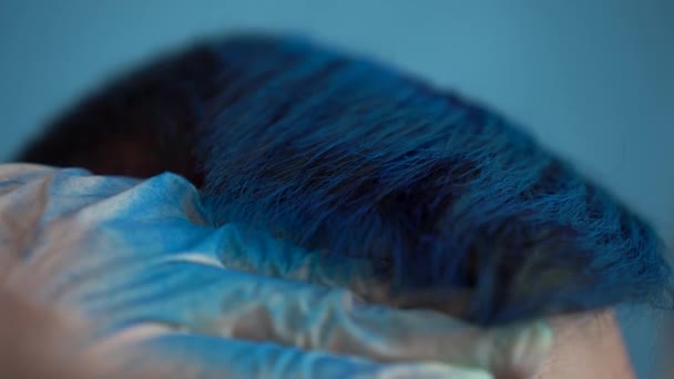 Молодой человек окрашен в синий цвет крупным планом. Мужчина окрашен временным красителем для волос из баллончика . — стоковое видео