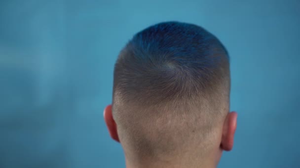 Mladý muž si obarví vlasy na modro. Alternativní lidé je malován s dočasnou barvou na vlasy ze spreje plechovky. Pohled zezadu.. — Stock video