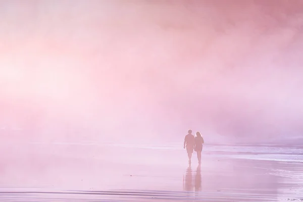 Paar spaziert bei Sonnenuntergang am Strand — Stockfoto