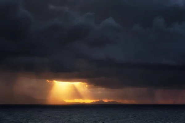 Downpour and sun rays on the sea — Stock Photo, Image