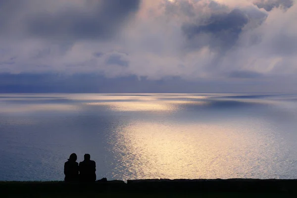Пара, наблюдающая за морем на закате — стоковое фото