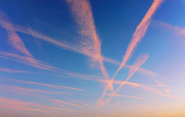 Cloudscape with airplane trails at sunset — Stock Photo, Image