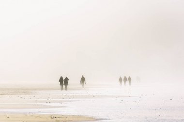people walking with sandstorm on beach clipart