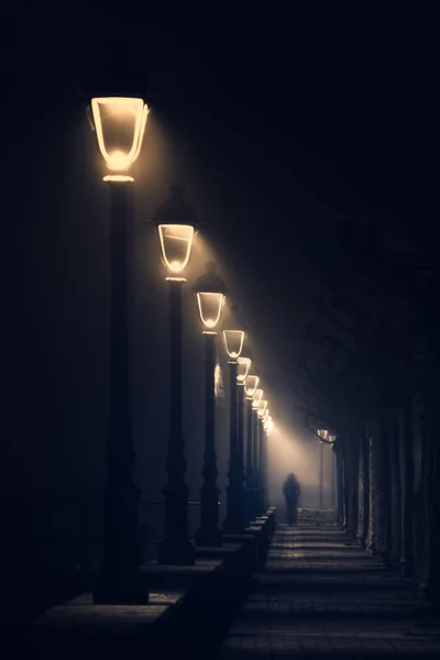 Persoon lopen op donkere straat verlicht met lantarens — Stockfoto