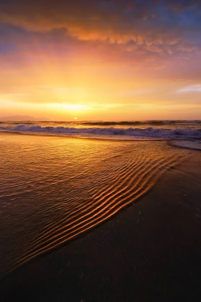 Plage rivage au coucher du soleil avec des ondulations d'eau — Photo