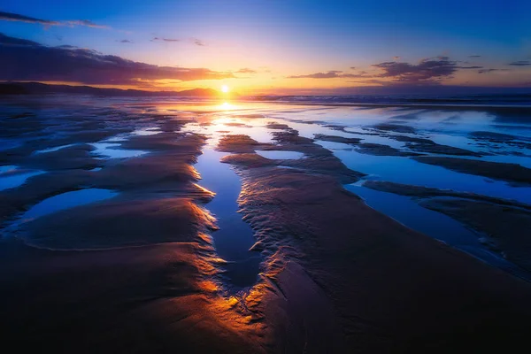 Marée basse dans la plage avec flaques au coucher du soleil — Photo