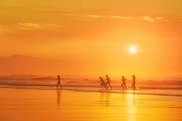 Meisjes van plezier in het strand bij zonsondergang — Stockfoto